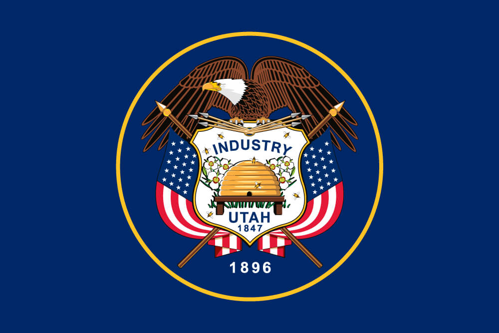 a field of blue charged with the state coat of arms featuring an eagle, two U.S. flags, and a beehive
